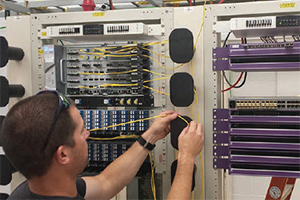 A technician works on a broadband network’s electronics.